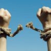 Hands with broken rope against blue sky