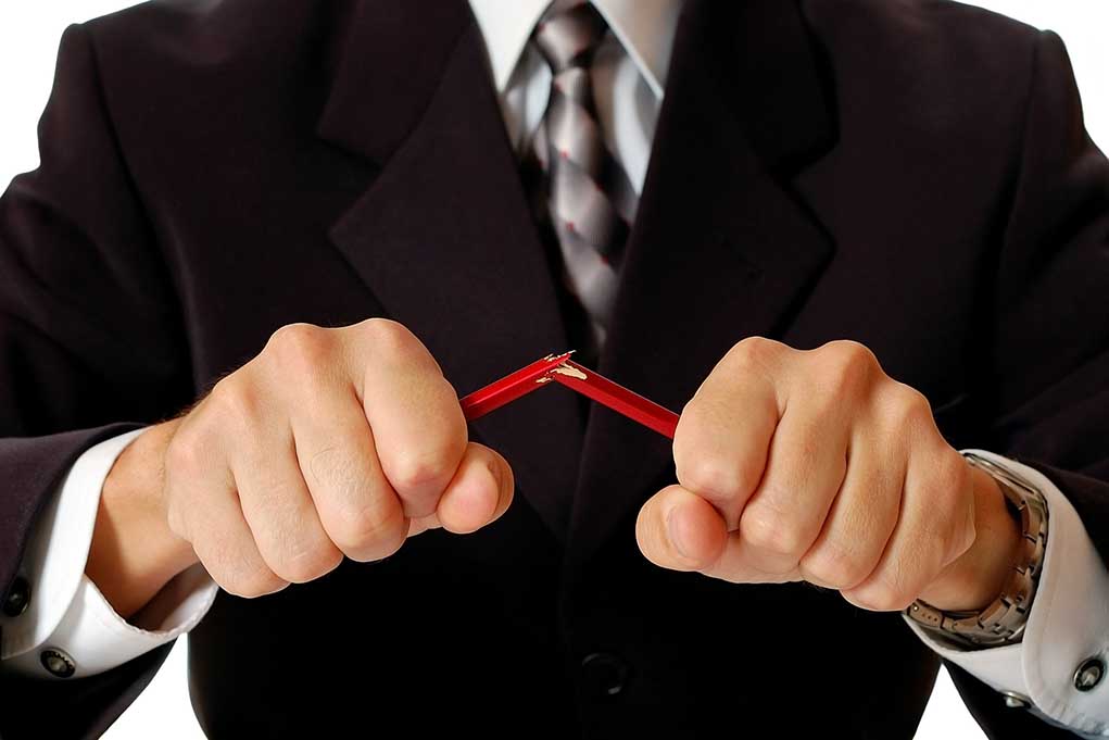 Person breaking red pencil with both hands