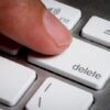 Finger pressing a delete key on keyboard