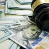 Gavel and hundred dollar bills on table