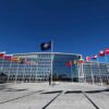 Flags outside NATO headquarters building under clear blue sky
