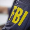 Person wearing jacket with FBI in yellow letters