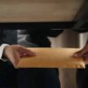 Two people exchanging envelope under table