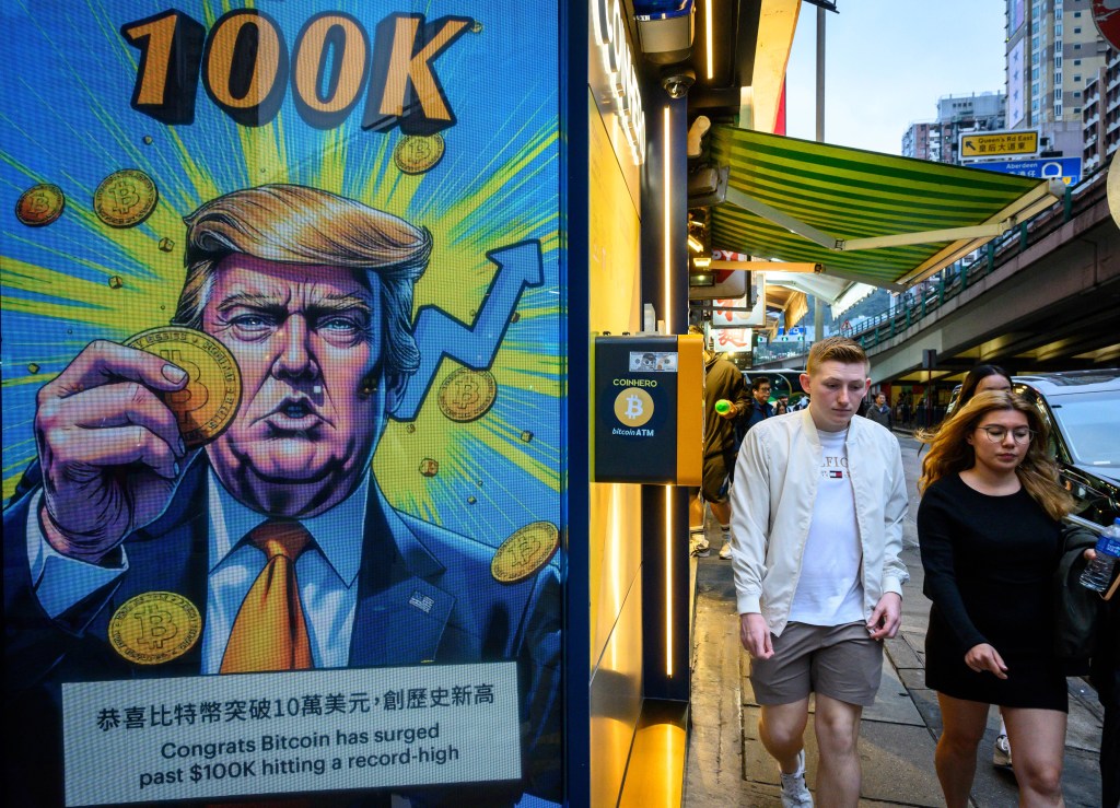 Cryptocurrency exchange office in Hong Kong with a screen featuring President Trump holding cryptocurrency coins.