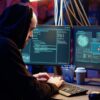 Hacker in dark underground warehouse receiving access denied error message on computer while attempting cyber attack on governmental websites