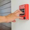 Hand reaching to pull fire alarm lever