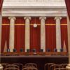 Empty courtroom with columns red curtains and chairs