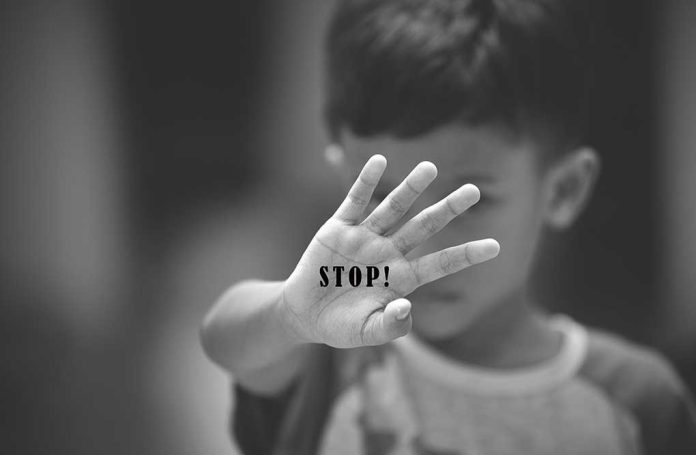 Child holding up hand with STOP written on palm