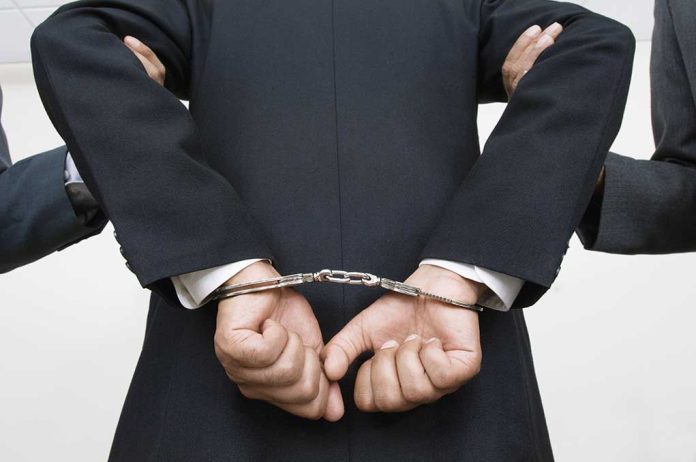Person handcuffed in suitescorted by two others