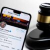 Smartphone displaying Twitter profile beside a judge gavel