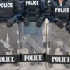 Police officers in riot gear holding shields