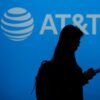 Silhouette of a person using a phone in front of an AT&T logo.