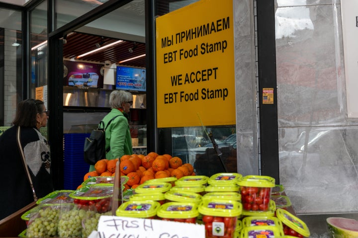 People shop for food at a store in New York City that advertises that it accepts SNAP benefits, also known as food stamps. The Brooklyn neighborhood has a large immigrant and elderly population.