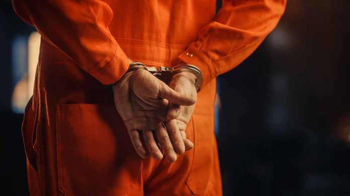Person in orange jumpsuit with handcuffs behind back