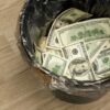 Trash bin filled with one hundred dollar bills