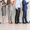 Businesspeople waiting in line indoors.