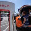 Woman charging an orange Tesla.