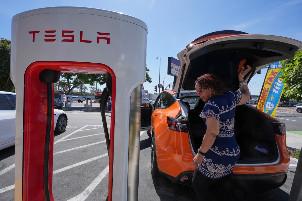 Woman charging an orange Tesla.