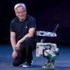 Jensen Huang kneeling next to a humanoid robot.