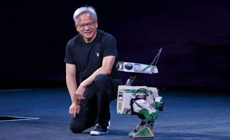 Jensen Huang kneeling next to a humanoid robot.