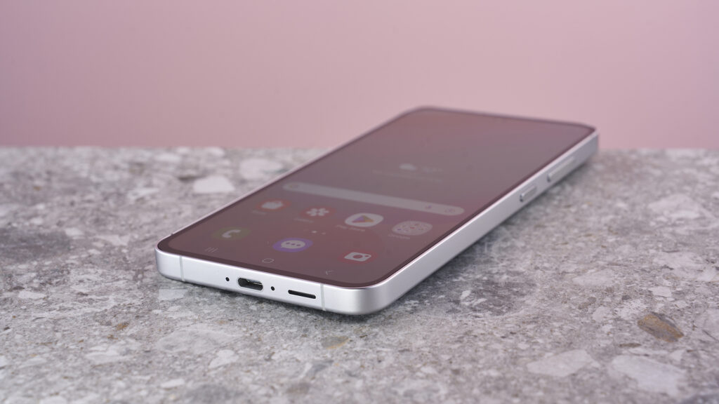Samsung Galaxy S24 FE on stone surface showing home screen menu
