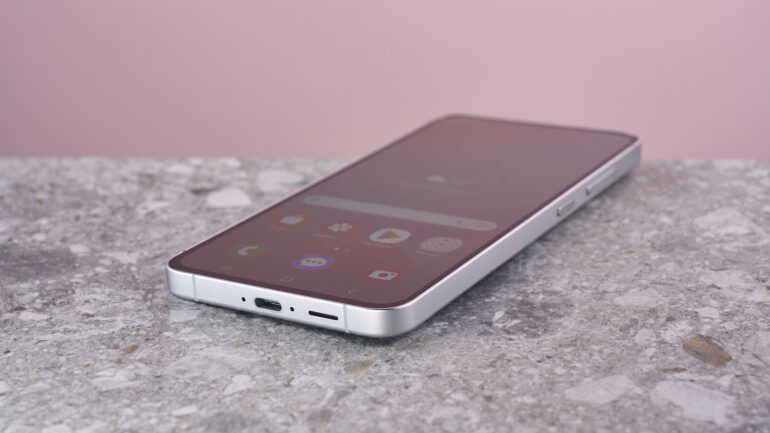 Samsung Galaxy S24 FE on stone surface showing home screen menu