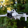 Dji Mini 4 Pro in flight in front of trees