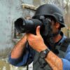 Person in helmet taking photos with a large camera