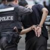 Police officer arrests handcuffed person