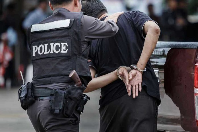 Police officer arrests handcuffed person