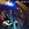 Police officer placing Devon Flanagan in a police cruiser.
