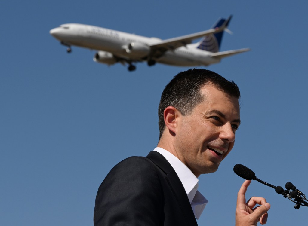 Secretary Pete Buttigieg speaking at Denver International Airport with a plane in the background.