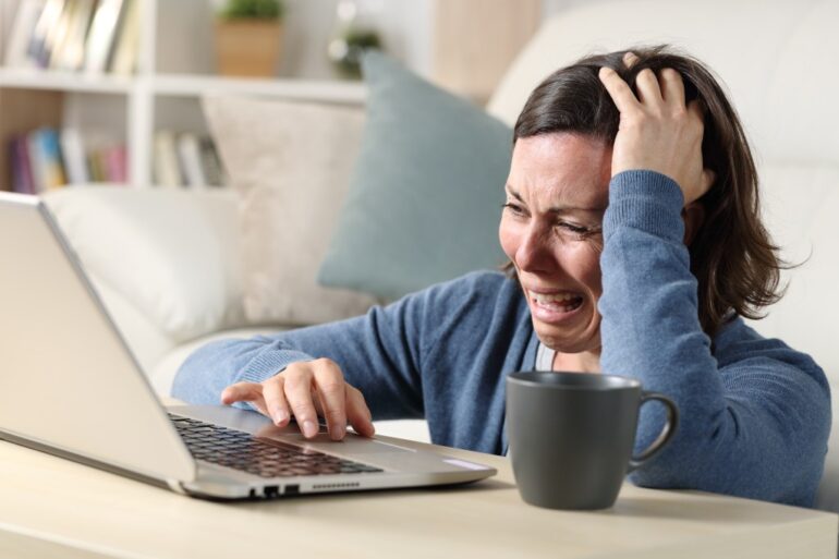 Woman crying while using a laptop.