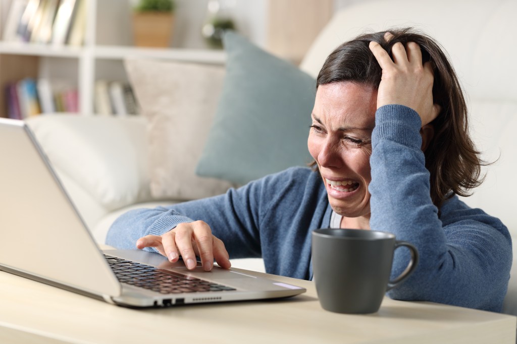 Woman crying while using a laptop.