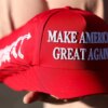 A member of Turning Point USA distributes MAGA hats to people gathered at a makeshift memorial for right-wing activist and Turning Point USA founder Charlie Kirk outside of their headquarters in Phoenix, Arizona, on September 19, 2025. The widow of slain right-wing activist Charlie Kirk is to take his place at the head of youth action campaign group Turning Point USA, officials announced on September 18. Two days after her husband was shot dead on a univerity campus, allegedly by a 22-year-old gunman, Erika Kirk told supporters: "The movement my husband built will not die." (Photo by CHARLY TRIBALLEAU / AFP) (Photo by CHARLY TRIBALLEAU/AFP via Getty Images)