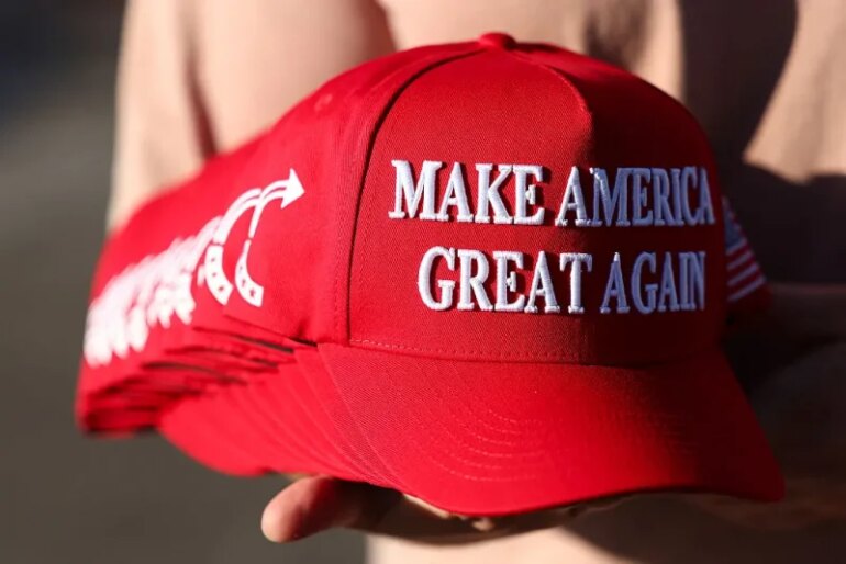 A member of Turning Point USA distributes MAGA hats to people gathered at a makeshift memorial for right-wing activist and Turning Point USA founder Charlie Kirk outside of their headquarters in Phoenix, Arizona, on September 19, 2025. The widow of slain right-wing activist Charlie Kirk is to take his place at the head of youth action campaign group Turning Point USA, officials announced on September 18. Two days after her husband was shot dead on a univerity campus, allegedly by a 22-year-old gunman, Erika Kirk told supporters: "The movement my husband built will not die." (Photo by CHARLY TRIBALLEAU / AFP) (Photo by CHARLY TRIBALLEAU/AFP via Getty Images)