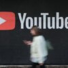 BERLIN, GERMANY - SEPTEMBER 27: A young woman with a smartphone walks past a billboard advertisement for YouTube on September 27, 2019 in Berlin, Germany. YouTube has evolved as the world's largest platform for sharing video clips. (Photo by Sean Gallup/Getty Images)