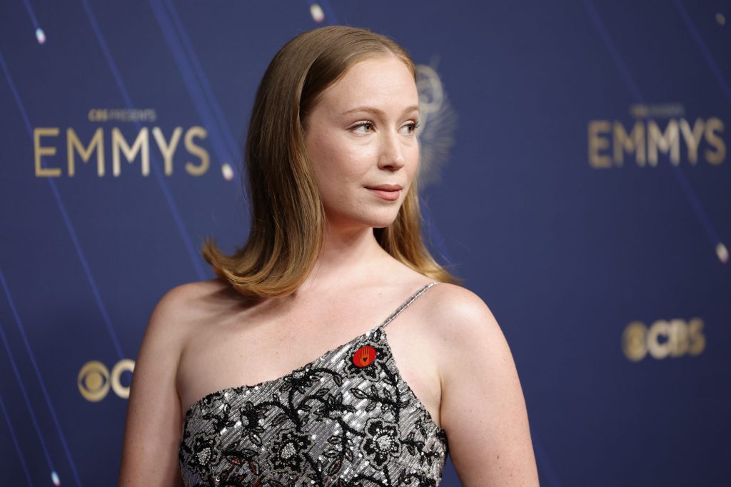 Hannah Einbinder at the Emmy Awards wearing a red hand pin.