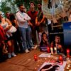 People mourning U.S. right-wing activist and commentator Charlie Kirk outside the U.S. embassy in Madrid, with candles and images of Kirk.