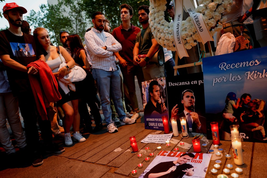 People mourning U.S. right-wing activist and commentator Charlie Kirk outside the U.S. embassy in Madrid, with candles and images of Kirk.