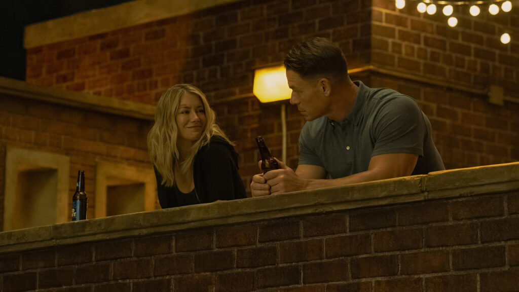 Emilia Harcourt smiling at Chris Smith at night in Peacemaker season 2