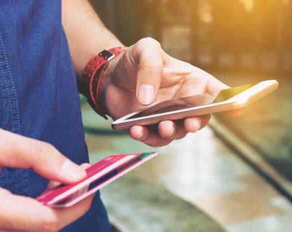 Person holding a smartphone and a credit card, preparing for a digital transaction