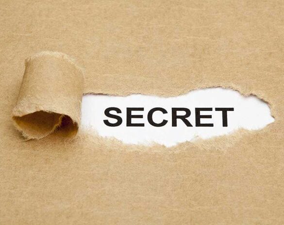 A torn piece of brown paper revealing the word SECRET underneath