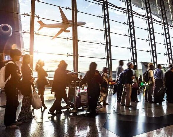 Crowd of travelers in airport terminal with airplane outside.