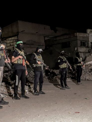 Hamas militants stand guard as vehicles of the International Committee of the Red Cross (not pictured) carry the bodies of hostages held in Gaza since the deadly October 7, 2023, attack, after their transfer by Hamas under a ceasefire and hostage-prisoner exchange agreement between Hamas and Israel, in Gaza City, Gaza Strip, on October 15, 2025. (Photo by Abood Abusalama / Middle East Images via AFP) (Photo by ABOOD ABUSALAMA/Middle East Images/AFP via Getty Images)