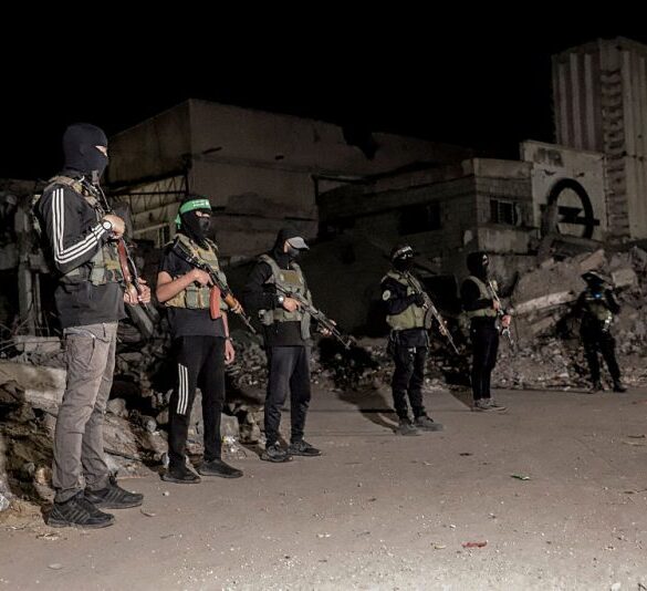 Hamas militants stand guard as vehicles of the International Committee of the Red Cross (not pictured) carry the bodies of hostages held in Gaza since the deadly October 7, 2023, attack, after their transfer by Hamas under a ceasefire and hostage-prisoner exchange agreement between Hamas and Israel, in Gaza City, Gaza Strip, on October 15, 2025. (Photo by Abood Abusalama / Middle East Images via AFP) (Photo by ABOOD ABUSALAMA/Middle East Images/AFP via Getty Images)