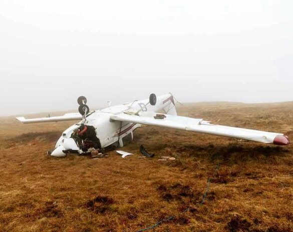 Overturned crashed airplane on grassy field.