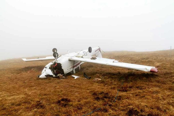 Overturned crashed airplane on grassy field.