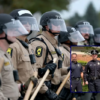 Police interact with demonstrators near the "Free Speech Zone" outside of the immigrant processing and detention center on October 17, 2025, in Broadview, Illinois. Demonstrations have been taking place outside of the facility for several weeks as the Trump administration's Operation Midway Blitz has been underway, arresting and detaining immigrants in the Chicago area. (Photo by Joe Raedle/Getty Images) / Officer Radule Bojovic of Montenegro; U.S. Department of Homeland Security