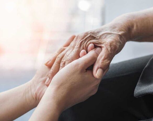 Young hands holding an elderly persons hand.